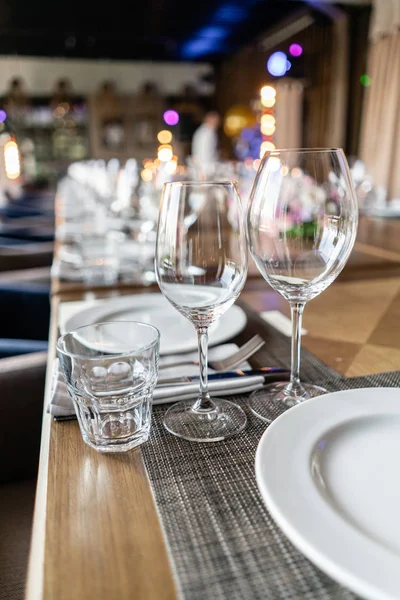 Copas de vino en primer plano. Banquete de bodas o cena de gala. Las sillas y la mesa para los huéspedes, servidas con cubiertos y vajilla . — Foto de Stock
