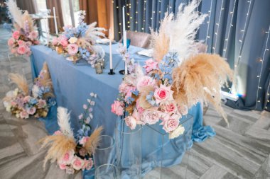 Mavi masa örtüsü, tabaklar ve mumlu mumlar. Restoranda lüks akşam yemeği Ziyafeti. Düğün kutlaması güzel ve zarif dekorasyon.