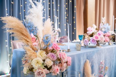 Mavi masa örtüsü, tabaklar ve mumlu mumlar. Restoranda lüks akşam yemeği Ziyafeti. Düğün kutlaması güzel ve zarif dekorasyon.