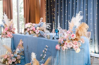 Mavi masa örtüsü, tabaklar ve mumlu mumlar. Restoranda lüks akşam yemeği Ziyafeti. Düğün kutlaması güzel ve zarif dekorasyon.