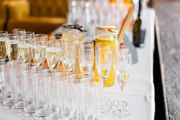Recepción. Mesa llena de copas de vino blanco espumoso con canapés y antipasti en el fondo. burbujas de champán —  Fotos de Stock