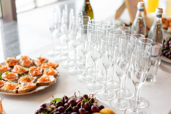 Ricezione. Piano tavolo pieno di bicchieri di spumante bianco con tartine e antipasti sullo sfondo. bolle di champagne — Foto Stock