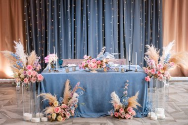 Mavi masa örtüsü, tabaklar ve mumlu mumlar. Restoranda lüks akşam yemeği Ziyafeti. Düğün kutlaması güzel ve zarif dekorasyon.