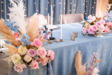 Mavi masa örtüsü, tabaklar ve mumlu mumlar. Restoranda lüks akşam yemeği Ziyafeti. Düğün kutlaması güzel ve zarif dekorasyon.