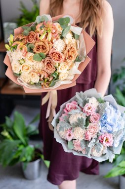 Kadın elinde karışık çiçek iki güzel buketleri. Çiçek dükkanı konsepti . Yakışıklı taze buket. Çiçek teslimatı.