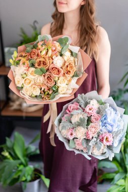 Kadın elinde karışık çiçek iki güzel buketleri. Çiçek dükkanı konsepti . Yakışıklı taze buket. Çiçek teslimatı.