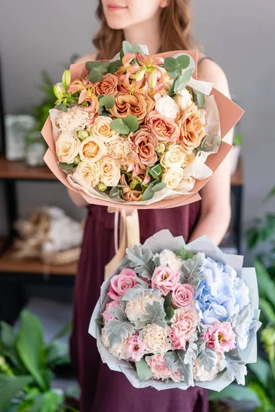 Kadın elinde karışık çiçek iki güzel buketleri. Çiçek dükkanı konsepti . Yakışıklı taze buket. Çiçek teslimatı.
