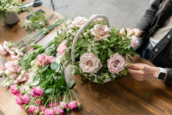 Mujer florista crear arreglo floral en una canasta de mimbre. Hermoso ramo de flores mixtas. Concepto de tienda floral. Bonito ramo fresco. Entrega de flores — Foto de Stock