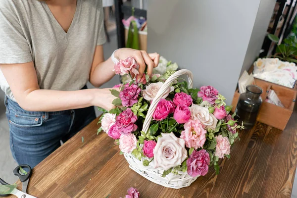 Mulher florista criar arranjo de flores em uma cesta de vime. Belo buquê de flores mistas. Conceito de loja floral. Bonito buquê fresco. Entrega de flores — Fotografia de Stock