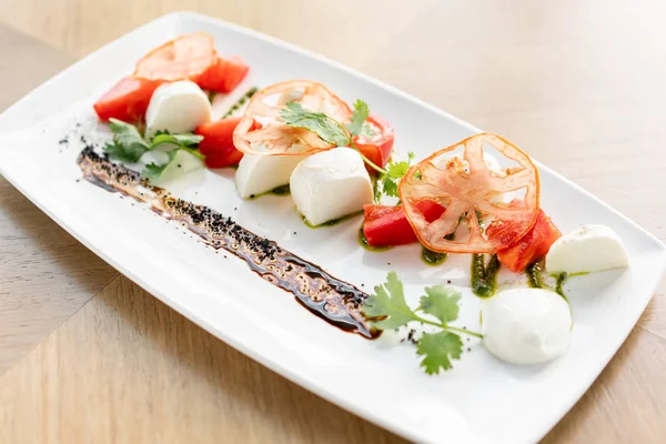 Insalata caprese tradizionale italiana. Insalata fresca con pomodori, basilico, mozzarella e olio d'oliva su fondo di legno. Concetto alimentare mediterraneo, naturale e biologico . — Foto Stock