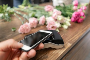 Konsept temassız ödeme. Akıllı telefon ve pos terminali ile ödeme yapma, baskılı çek. Çiçek dükkanı konsepti . Çiçek teslimatı