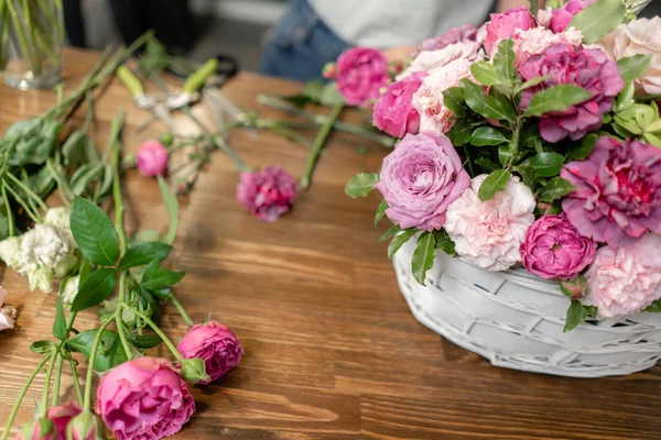 女花匠在柳条篮中制作花。美丽的混合花束。花卉店概念。漂亮的新鲜花束。鲜花递送 — 图库照片