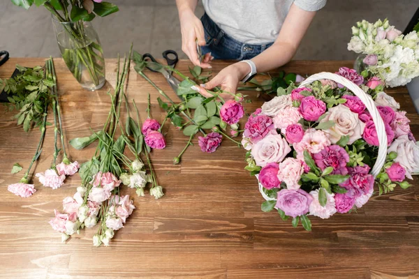 Mujer florista crear arreglo floral en una canasta de mimbre. Hermoso ramo de flores mixtas. Concepto de tienda floral. Bonito ramo fresco. Entrega de flores — Foto de Stock