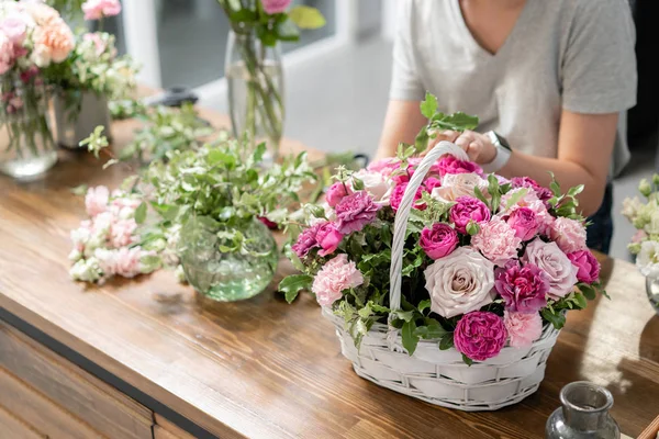Handsome fresh bouquet. Flowers delivery. Woman florist create flower arrangement in a wicker basket. Beautiful bouquet of mixed flowers. Floral shop concept .