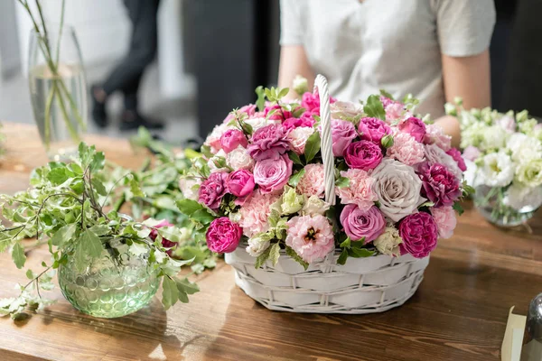 Handsome fresh bouquet. Flowers delivery. Woman florist create flower arrangement in a wicker basket. Beautiful bouquet of mixed flowers. Floral shop concept .