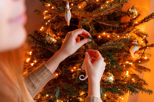 Gelukkig jonge vrouw versieren kerstboom thuis. Winter vakantie in een huis interieur. Gouden en witte kerst speelgoed, lichten slingers. Natuurlijk Deens sparrenhout — Stockfoto