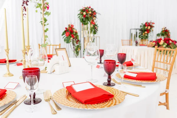 Stół ustawienie czerwone serwetki i okulary, Złote talerze. Wnętrze dekoracji namiotu ślubnego gotowy dla Gości. Dekoracje kwiatów. Kompozycja czerwona — Zdjęcie stockowe