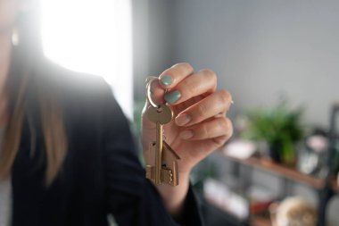 Bir daire kiralama kavramı. Ev anahtarı, kadın ların elinde. Genç bir kadın. Modern ışık lobisi iç mekan. Gayrimenkul, varsayım, eve taşınma veya mülk kiralama.