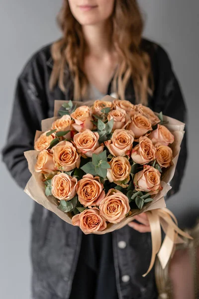 Bloemen koffie kleur, cappuccino rozen met eucalyptus. Kleine mooie boeketten in vrouw hand. Bloemenwinkel concept. Bloemen bezorgen — Stockfoto