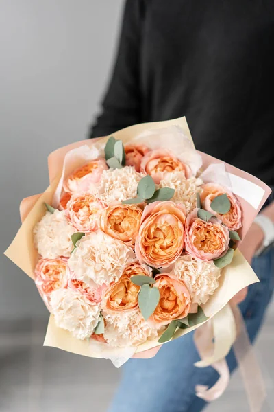 White and peach color. Beautiful bouquet of mixed flowers in womans hands. the work of the florist at a flower shop. Fresh cut flower. — Stock Photo, Image