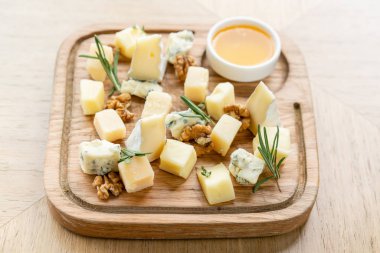 Peynir tabağı. Cevizli peynir ve ahşap masada bal. Tahta tabakta tadımlık yemek. Şarap için yiyecek..