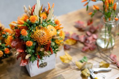 Ahşap masa üzerinde karışık çiçek Sonbahar buketi oluşturma süreci. Çiçekçi dükkanındaki çiçekçinin işi. Taze kesilmiş çiçek.