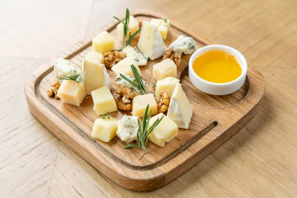 Sýrový talíř. Lahodný sýr s vlašskými ořechy, med na dřevěném stole. Ochutnávka jídla na dřevěném talíři. Jídlo na víno. — Stock fotografie