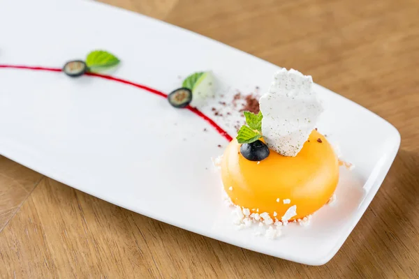Mousse-torta gialla. Dessert francese, mirtillo, menta e un pezzo di meringa su un piatto bianco. Elegantemente decorato. Menù ristorante — Foto Stock