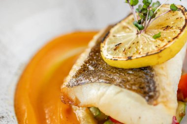 Kavrulmuş turna levrek veya pişmiş sebze ile morina balığı. Çanak limon bir dilim ile dekore edilmiştir. Restoran menüsü