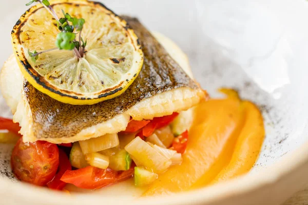 Pieczony sandacz lub ryba dorsza z pieczonymi warzywami. Danie ozdobione plasterkiem cytryny. Menu restauracji — Zdjęcie stockowe