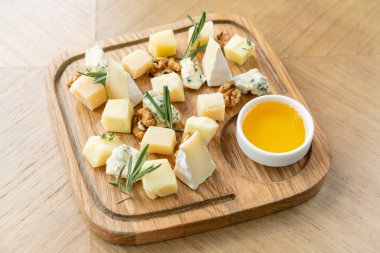 Peynir tabağı. Cevizli peynir ve ahşap masada bal. Tahta tabakta tadımlık yemek. Şarap için yiyecek..