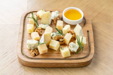 Peynir tabağı. Cevizli peynir ve ahşap masada bal. Tahta tabakta tadımlık yemek. Şarap için yiyecek..