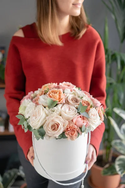 Cute floral arrangement of mixed flowers in woman hand. Round box. The work of the florist at a flower shop. Delicate Pastel color. Fresh cut flower.