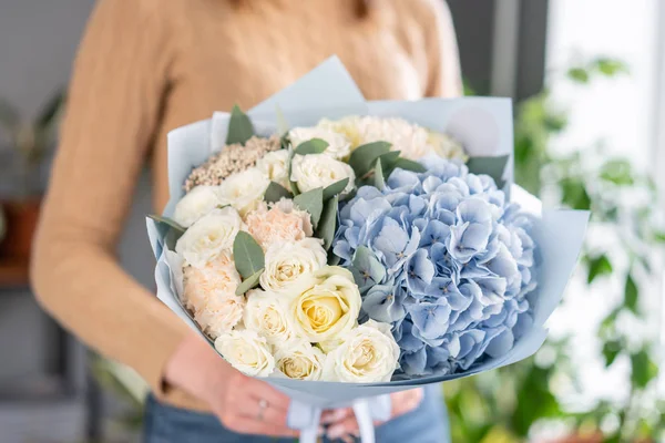 White and blue color. Beautiful bouquet of mixed flowers in womans hands. the work of the florist at a flower shop. Fresh cut flower. — Stock Photo, Image