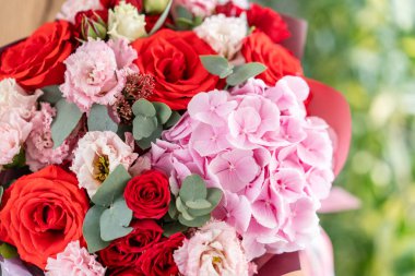 Pembe ve kırmızı renk. Kadın elinde karışık çiçek güzel buket. bir çiçekçi de çiçekçi çalışmaları. Taze kesilmiş çiçek.