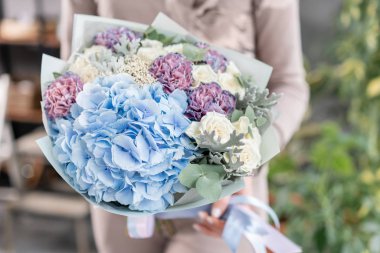 Beyaz ve mavi renk. Kadın elinde karışık çiçek güzel buket. bir çiçekçi de çiçekçi çalışmaları. Taze kesilmiş çiçek.