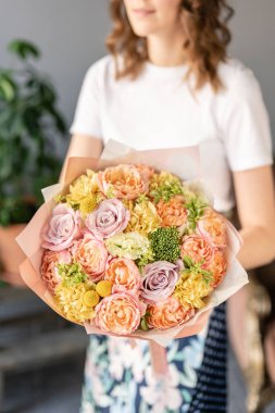 Buket Şeftali ve turuncu renk. Kadın elinde karışık çiçek güzel buket. bir çiçekçi de çiçekçi çalışmaları. Taze kesilmiş çiçek.