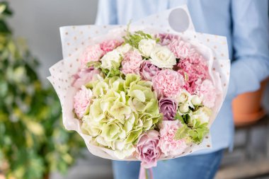 Pembe ve beyaz renkte. Kadın elinde karışık çiçek güzel buket. bir çiçekçi de çiçekçi çalışmaları. Taze kesilmiş çiçek.