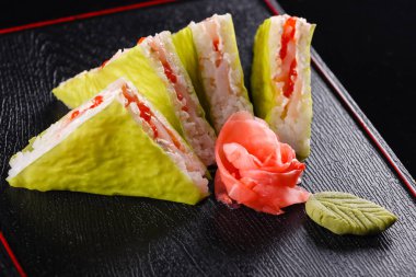 Üçgen parçalar. Japon yemekleri, öğle yemeğinde lezzetli yemek. Deniz ürünleri. Suşi, balık, alabalık, ton balığı siyah arka plan ile.