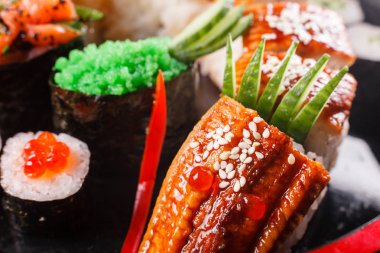 Suşi Ejder yılan balığı, salatalık ve avokado siyah bir arka plan ile. Japon yemekleri, lezzetli yemek öğle yemeği için