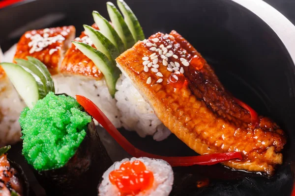 Sushi dragon with eel, cucumber and avocado on a black background. Japanese food, tasty of meal for lunch — Stock Photo, Image
