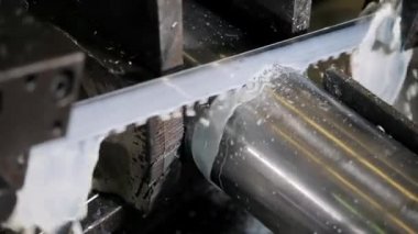 Endüstriyel testere makinesi malzeme çubuğunu kesiyor. Bant, soğutucu sıvıyla ham metalleri kesen makineyi gördü..