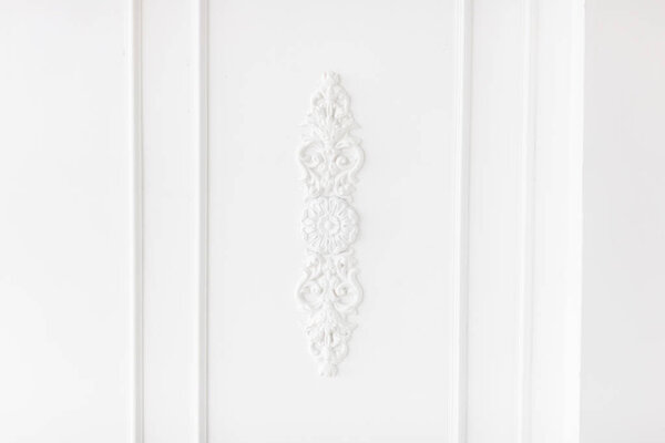 Expensive interior. Stucco elements on light luxury wall. White patterned. Mouldings element from gypsum. Roccoco style