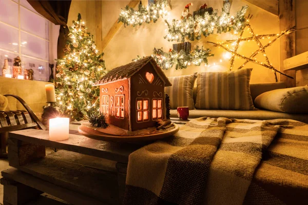 Heiligabend im Wohnzimmer.. hausgemachte Lebkuchenhaus auf Hintergrundraum für Weihnachten dekoriert. — Stockfoto