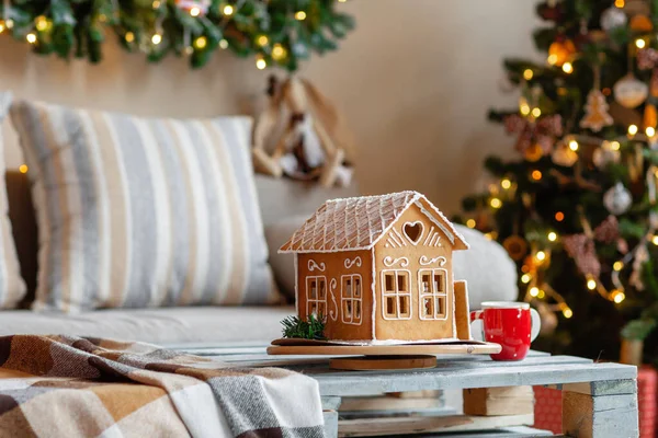 Weihnachtsmorgen im hellen Wohnzimmer. hausgemachte Lebkuchenhaus im Hintergrund Zimmer für Weihnachten dekoriert. — Stockfoto