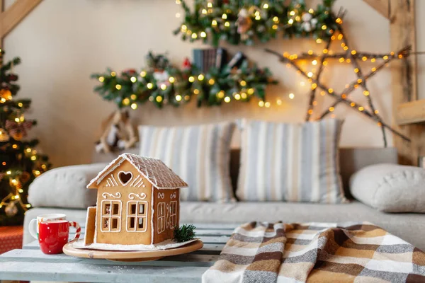 Weihnachtsmorgen im hellen Wohnzimmer. hausgemachte Lebkuchenhaus im Hintergrund Zimmer für Weihnachten dekoriert. — Stockfoto