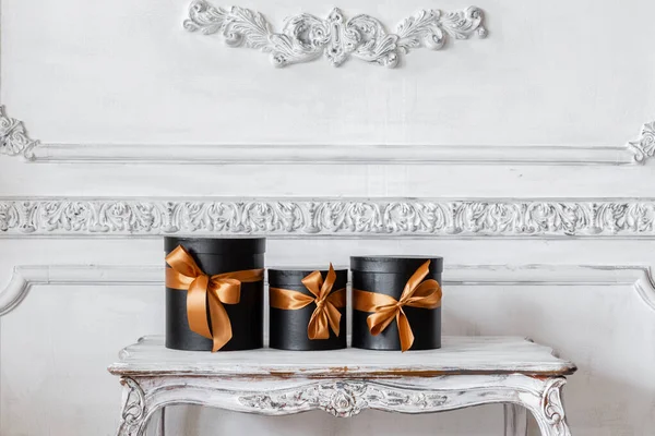 Чорні коробки зі стрічками як різдвяні подарунки на столі розкішний дизайн білої стіни барельєфні ліпнини — стокове фото