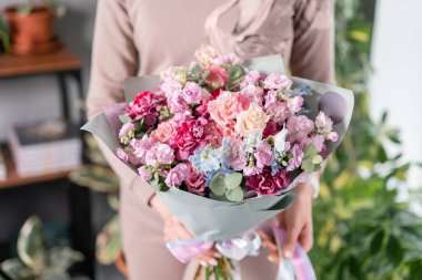 Mor ve pembe renkli. Kadınların elinde güzel bir buket karışık çiçek. Çiçekçi dükkanındaki çiçekçinin işi. Taze kesilmiş çiçek..
