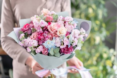 Mor ve pembe renkli. Kadınların elinde güzel bir buket karışık çiçek. Çiçekçi dükkanındaki çiçekçinin işi. Taze kesilmiş çiçek..