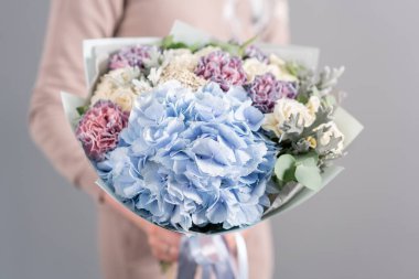 Beyaz ve mavi renk. Kadın elinde karışık çiçek güzel buket. bir çiçekçi de çiçekçi çalışmaları. Taze kesilmiş çiçek.